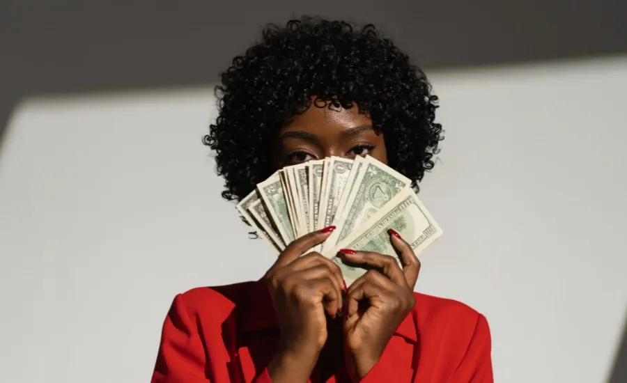 woman holding money she saved from loud bugdeting